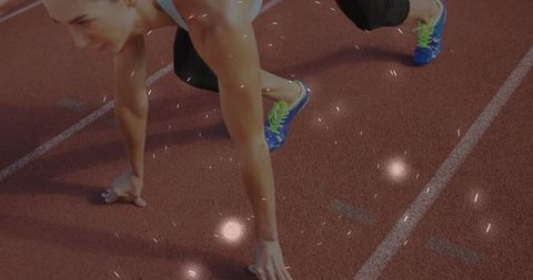 Female sprinter crouching at starting line on track