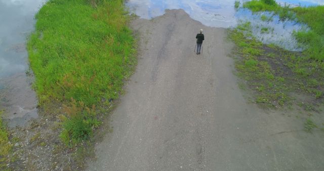 Aerial View of Person Walking on Rural Dirt Path by Water - Download Free Stock Photos Pikwizard.com