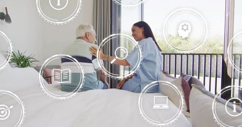 Caregiver supporting senior man in bedroom with healthcare hud icons for homecare