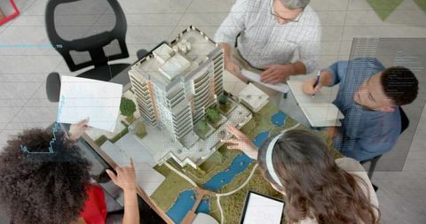 Architects examining scale model with digital overlays for urban development planning