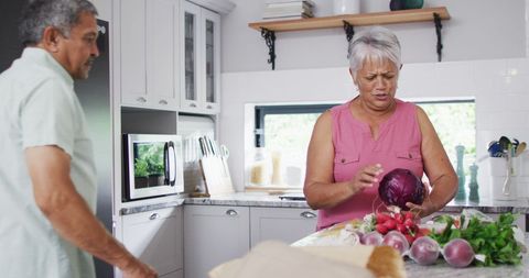Senior Couple Preparing Fresh Vegetables in Bright Kitchen