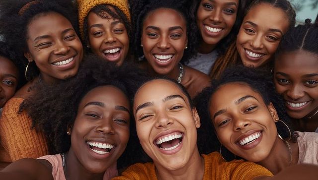 Smiling group of friends leaning close while taking joyful selfie outdoors, laughing together