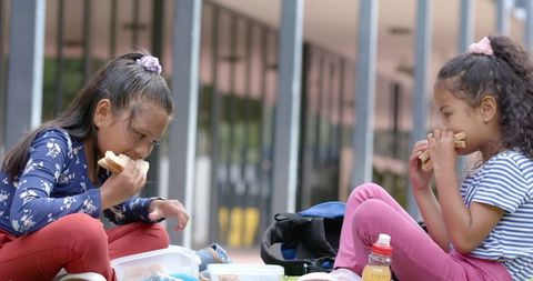 Two biracial girls enjoying outdoor school lunch
