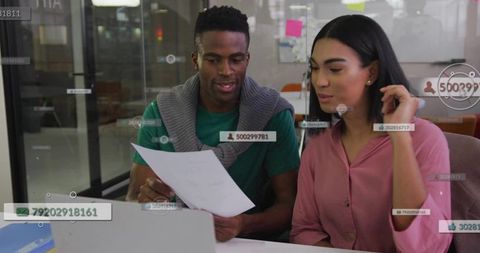 Young professionals reviewing documents in modern coworking space with laptop overlays