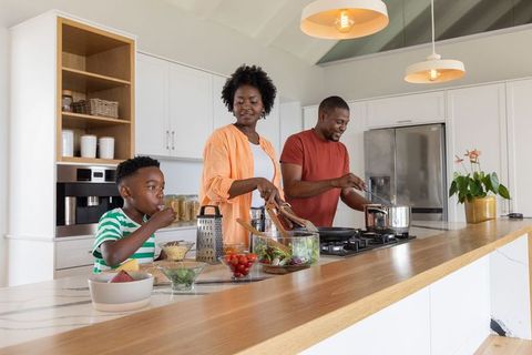 Black family cooking healthy meal together in bright modern kitchen
