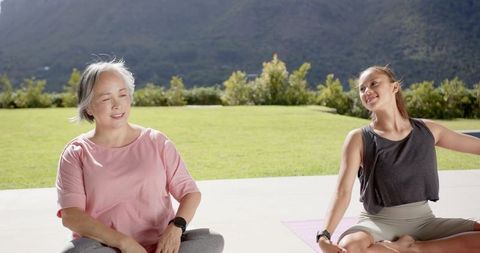 Women Practicing Yoga Outdoors with Scenic Mountain View