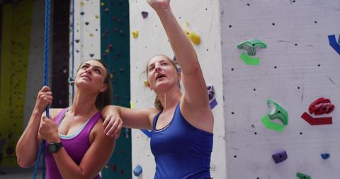 Women discussing climbing strategy at indoor rock wall