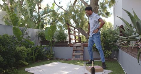 Man preparing outdoor picnic with wine in backyard garden