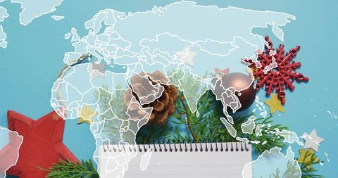 Planning holiday campaign with notepad, pinecone, evergreen sprig and world map overlay