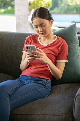 Young Woman Relaxing at Home Browsing Smartphone in Casual Setting