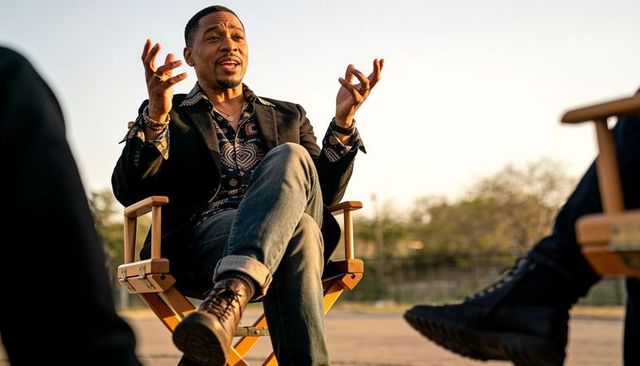 Man speaking and gesturing in casual outdoor interview on director chair at golden hour