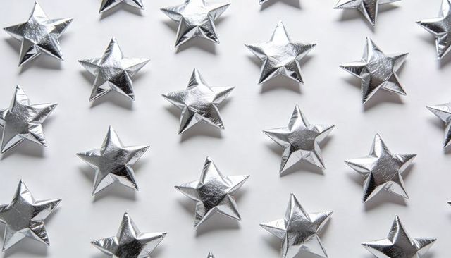 Shimmering silver stars lining geometric grid casting soft shadows on white surface