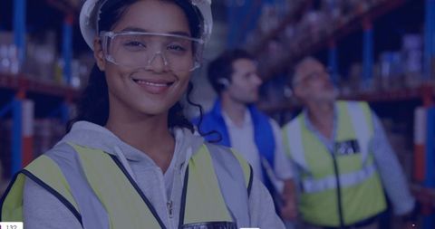 Smiling female warehouse worker wearing hard hat and safety goggles, distribution center