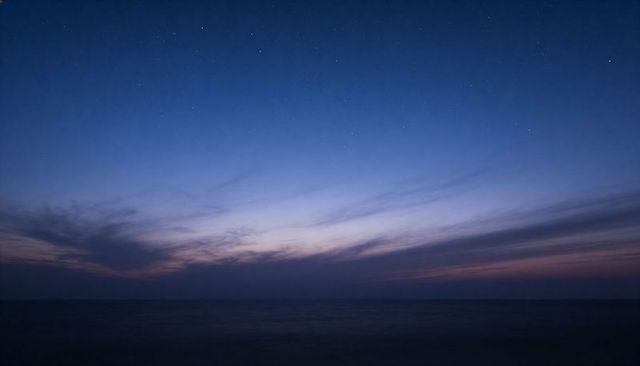 Twilight ocean horizon with starry sky and wispy clouds at dusk