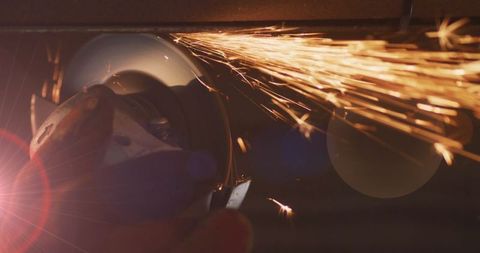 Angle grinder producing sparks on metal workpiece in workshop
