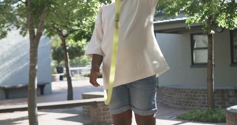 African american teen swinging yellow ribbon in sunlit school courtyard