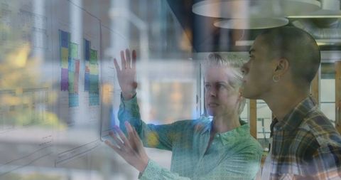 Diverse Coworkers Analyzing Architectural Blueprints in Modern Office