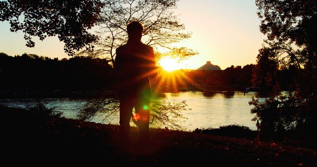 Capturing a calm and peaceful moment, this image of a silhouette person by the riverside at sunset can convey tranquility, reflection, and solitude. Ideal for projects involving themes of relaxation, nature, mindfulness, or inspirational settings. Perfect for blogs, websites, or social media posts focused on outdoor activities, scenic beauty, or serene experiences.