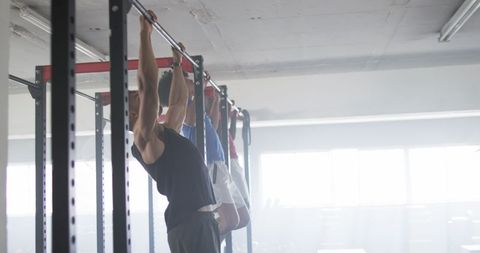 Men performing pull-ups in gym for strength training