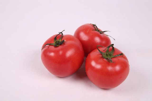 Close-up of three fresh red tomatoes. Perfect for depicting healthy eating, organic food, or gardening concepts. Ideal for use in culinary blogs, recipe illustrations, nutritional articles, and farm-to-table marketing materials.