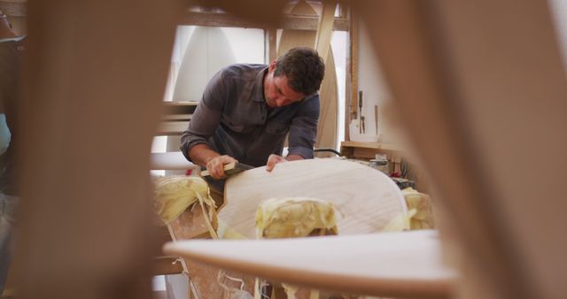 Craftsman sanding a wooden surfboard in a workshop - Download Free Stock Images Pikwizard.com