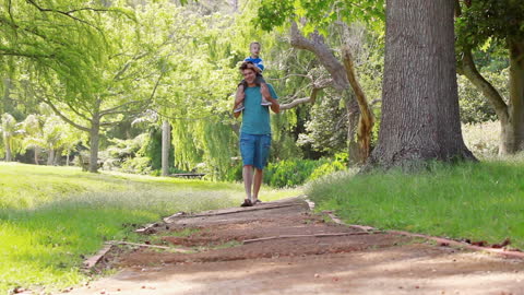 Father and Son Strolling in Green Park Enjoying Nature