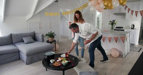 Couple Celebrating Anniversary at Home with Wine and Snacks