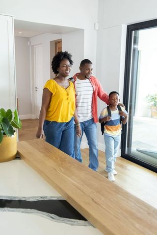 African american family walking into modern open-plan home with smiling parents and child