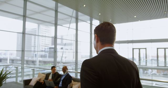 Businessman Entering Modern Office Lobby with Colleagues in Background - Download Free Stock Images Pikwizard.com