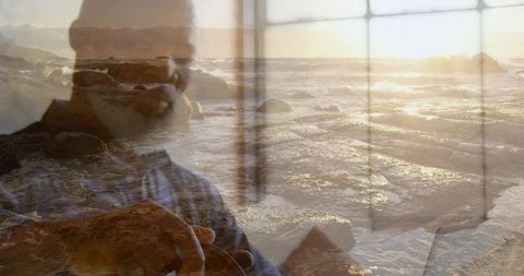 Double exposure portrait showing photographer framing seascape through window at sunset