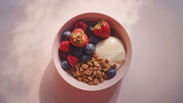 Ceramic Bowl with Granola Berries and Yogurt on Pink Tabletop
