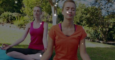 Women meditating outdoors on yoga mats with star lights for mindfulness and wellness