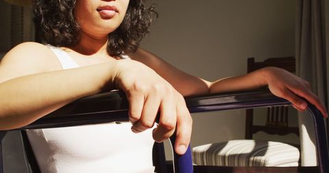 Biracial Woman in Wheelchair Relaxing in Sunlit Room