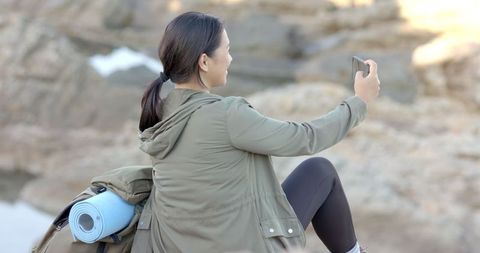 Woman Takes Selfie with Yoga Mat During Mountain Expedition