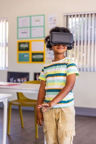 African american boy exploring virtual reality in classroom wearing headset