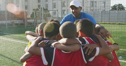 Soccer team huddle with coach strategizing outdoors