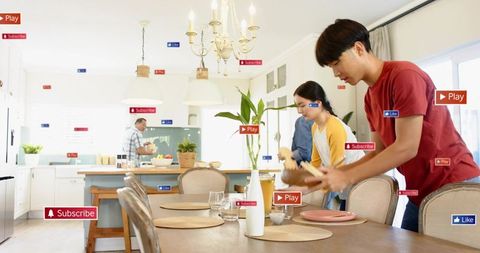 Family preparing dinner together in bright modern open-plan kitchen placing tableware