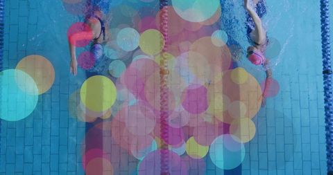 Top-down swimmers training in adjacent lanes with colorful bokeh overlay and lane divider