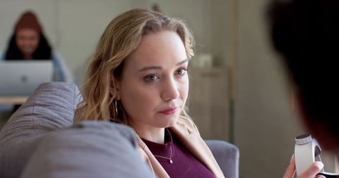 Young woman on sofa listening during serious conversation with partner in cozy living room