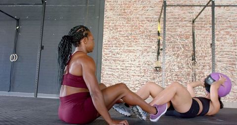 Women Performing Partner Exercises Focusing on Fitness in Gym