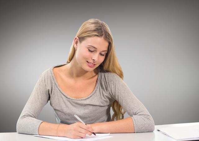 Female teenage student doing her homework against grey background