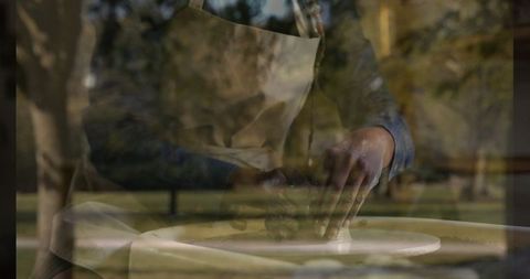 Woman shaping clay on wheel in tranquil outdoor environment