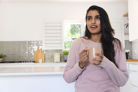 Woman Enjoying Coffee in Modern Kitchen Gazing Through Window