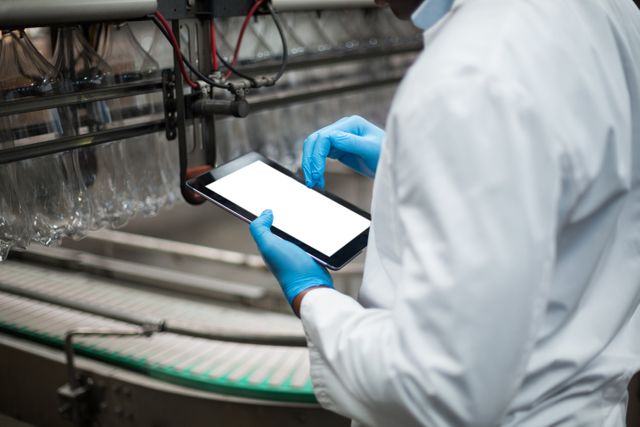 Factory engineer using digital tablet in drinks production plant