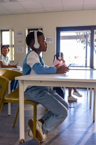 Focused african american boy learning with headphones at classroom desk