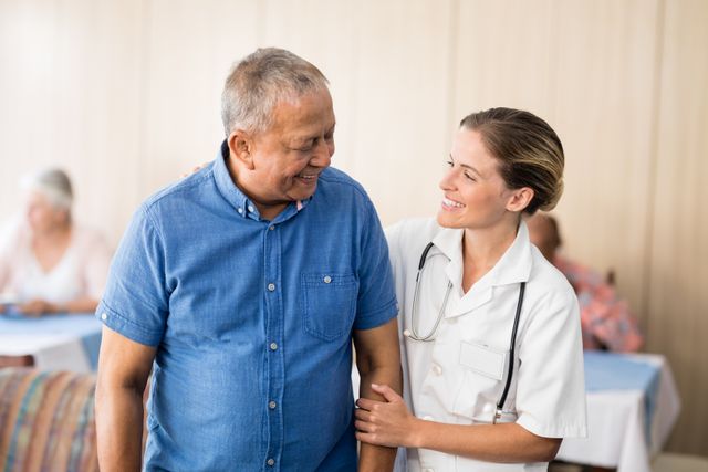Smiling senior man looking at young female doctor at retirement home