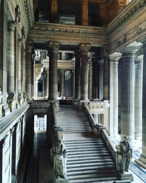 Majestic interior of a historical government building featuring grand staircase with marble columns and statues. Ideal for use in articles, historical documentaries, educational materials, architectural blogs, travel guides focusing on historical sites, and government-related presentations.