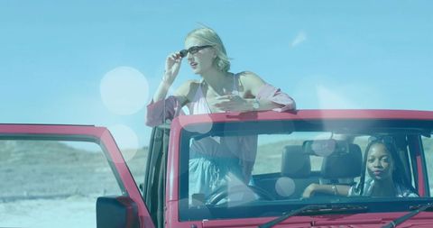 Friends enjoying road trip in red jeep on salt flat adventure