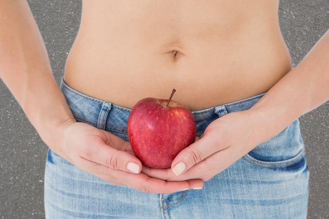 Digital composite of Midsection of woman holding apple representing weight loss