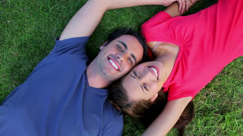 Happy Couple Relaxing on Green Grass in Park